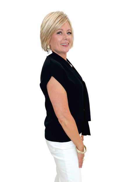 Side view of woman wearing Black Faux Layered Sweater Tank by Entro with jeans against white studio background.