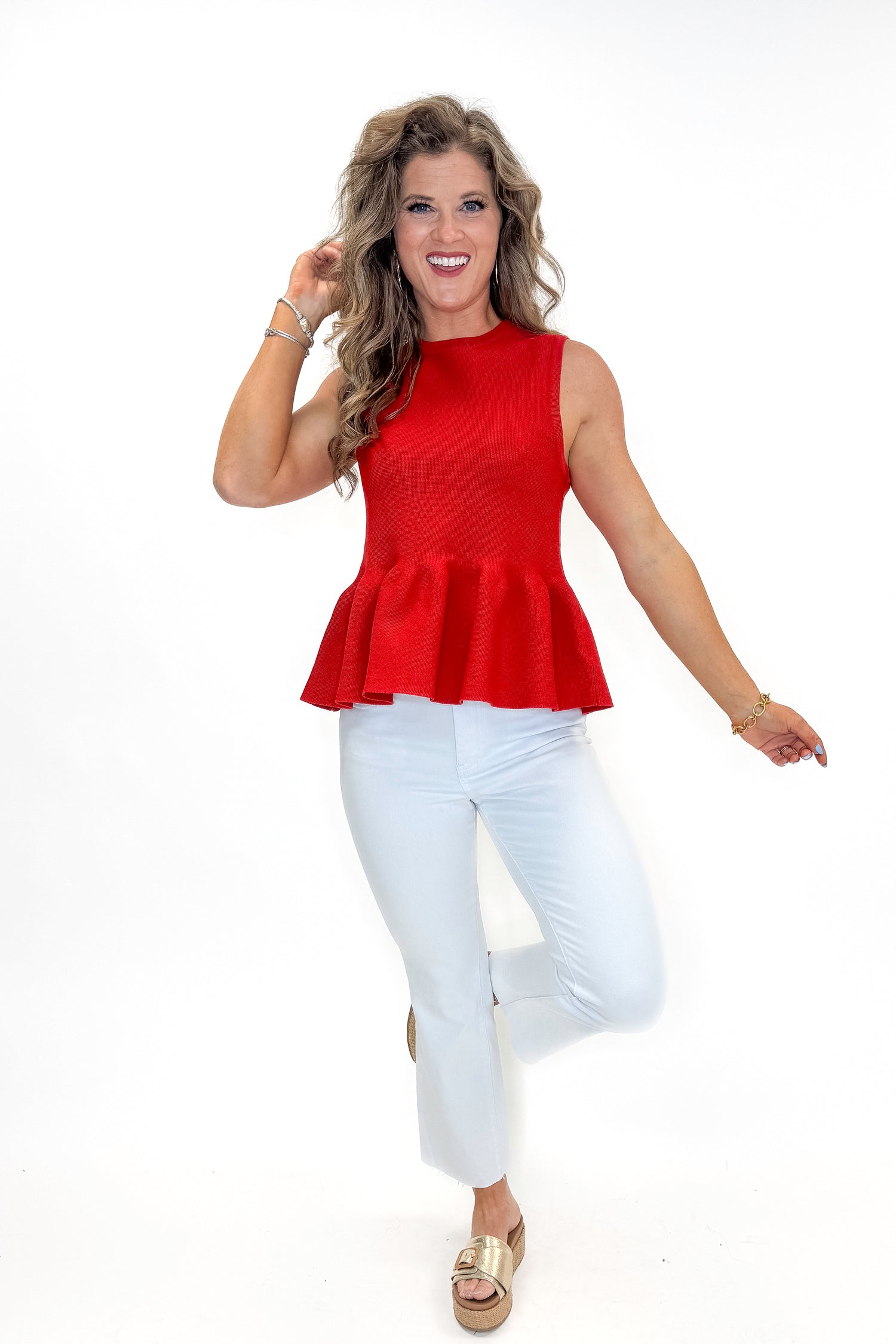 Front view of woman wearing Red Peplum Sweater Tank by Entro with jeans against white studio background.