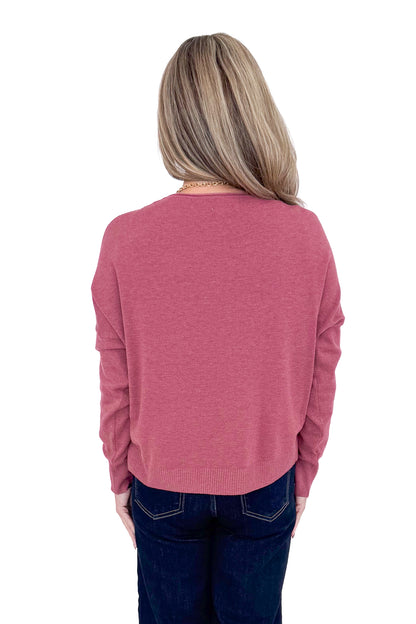 Back view of woman wearing Heathered Berry Center Seam Sweater and blue jeans. 