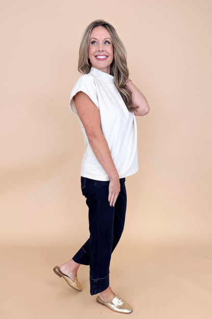 Side view of woman wearing Cream Suede Top by THML and jeans with tan background.
