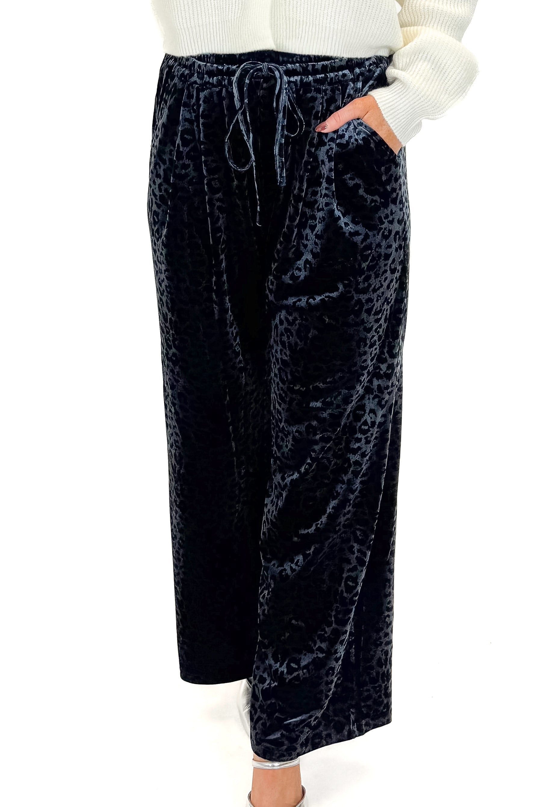 Front view of woman wearing Navy Velvet Leopard Print Pants with sweater against white studio background.
