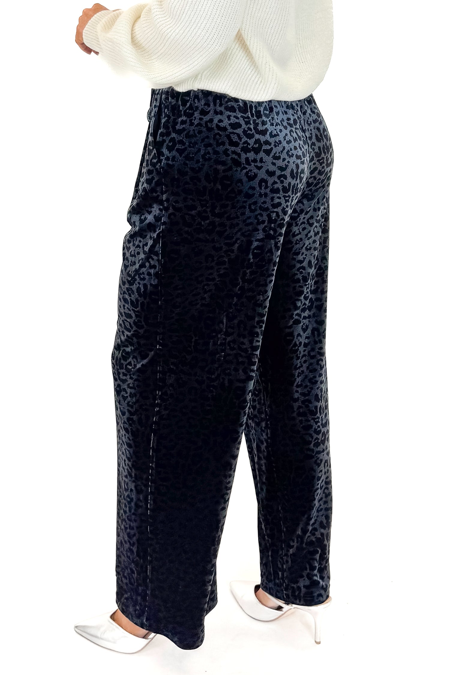 Side view of woman wearing Navy Velvet Leopard Print Pants with sweater against white studio background.