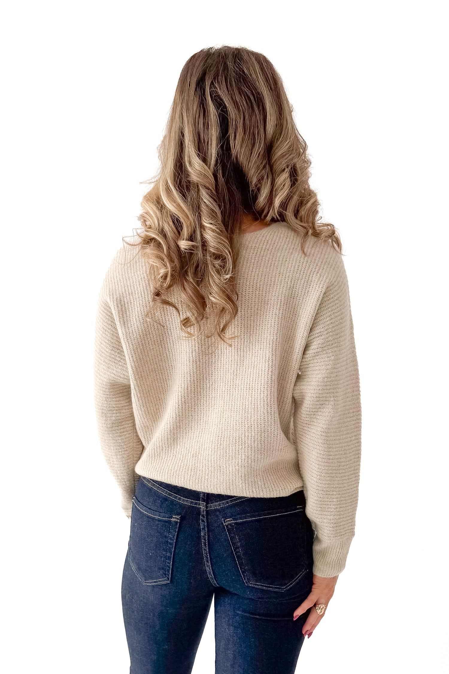 Back view of woman wearing Almond V-neck Sweater with jeans against white studio background.
