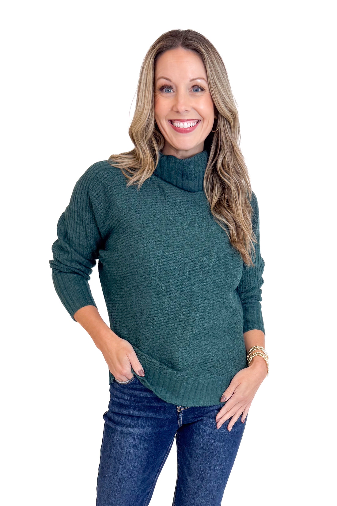 Woman wearing a dark green sweater and blue jeans on a white background