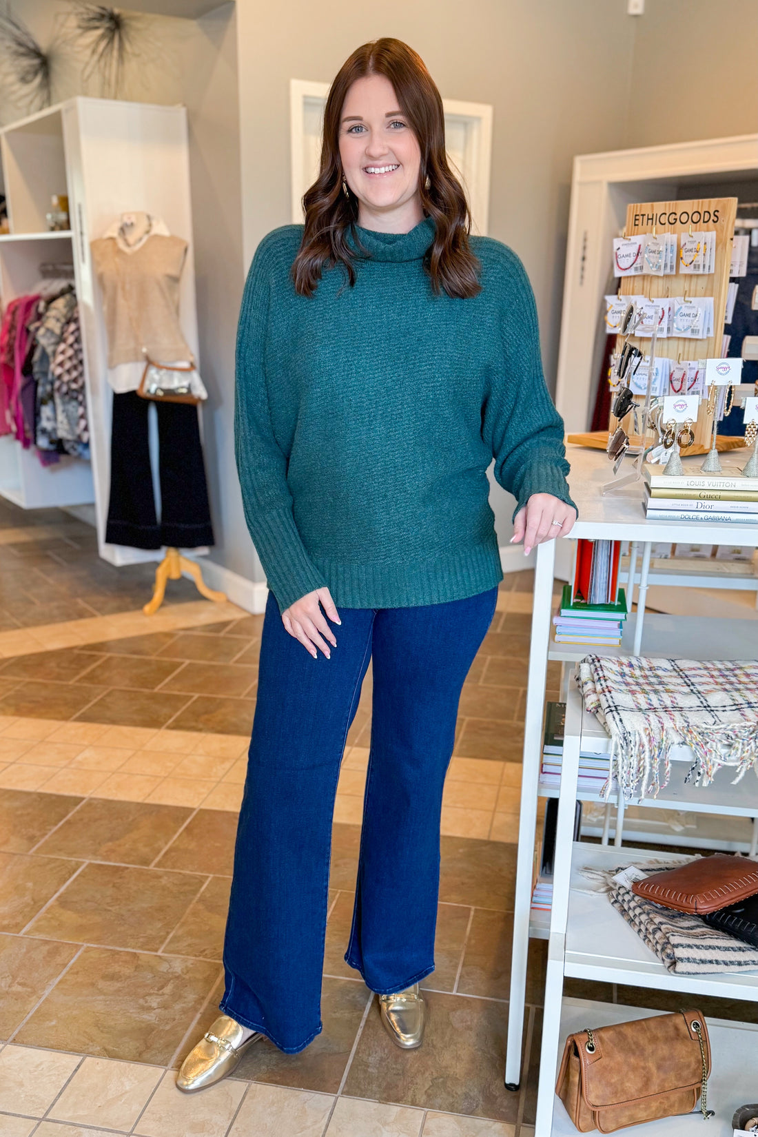 Woman wearing a teal sweater and blue pants standing in a store.