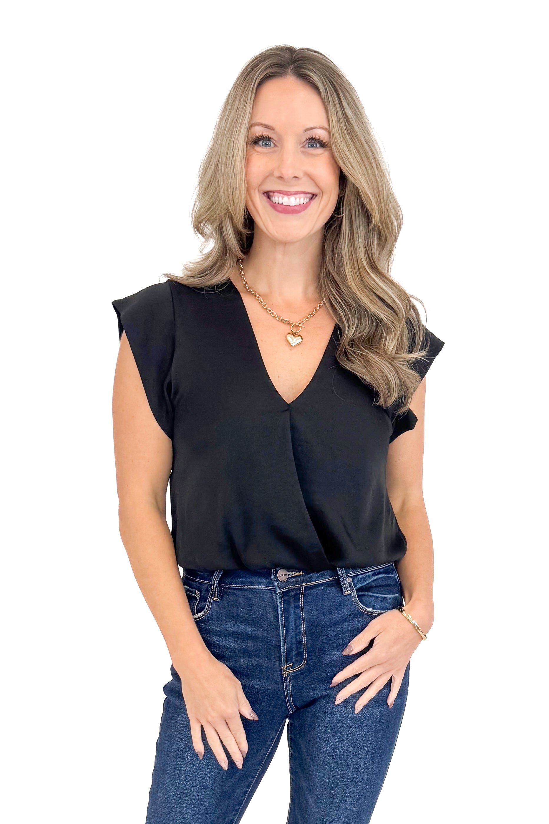 Front view of woman wearing black top with jeans against white studio background.