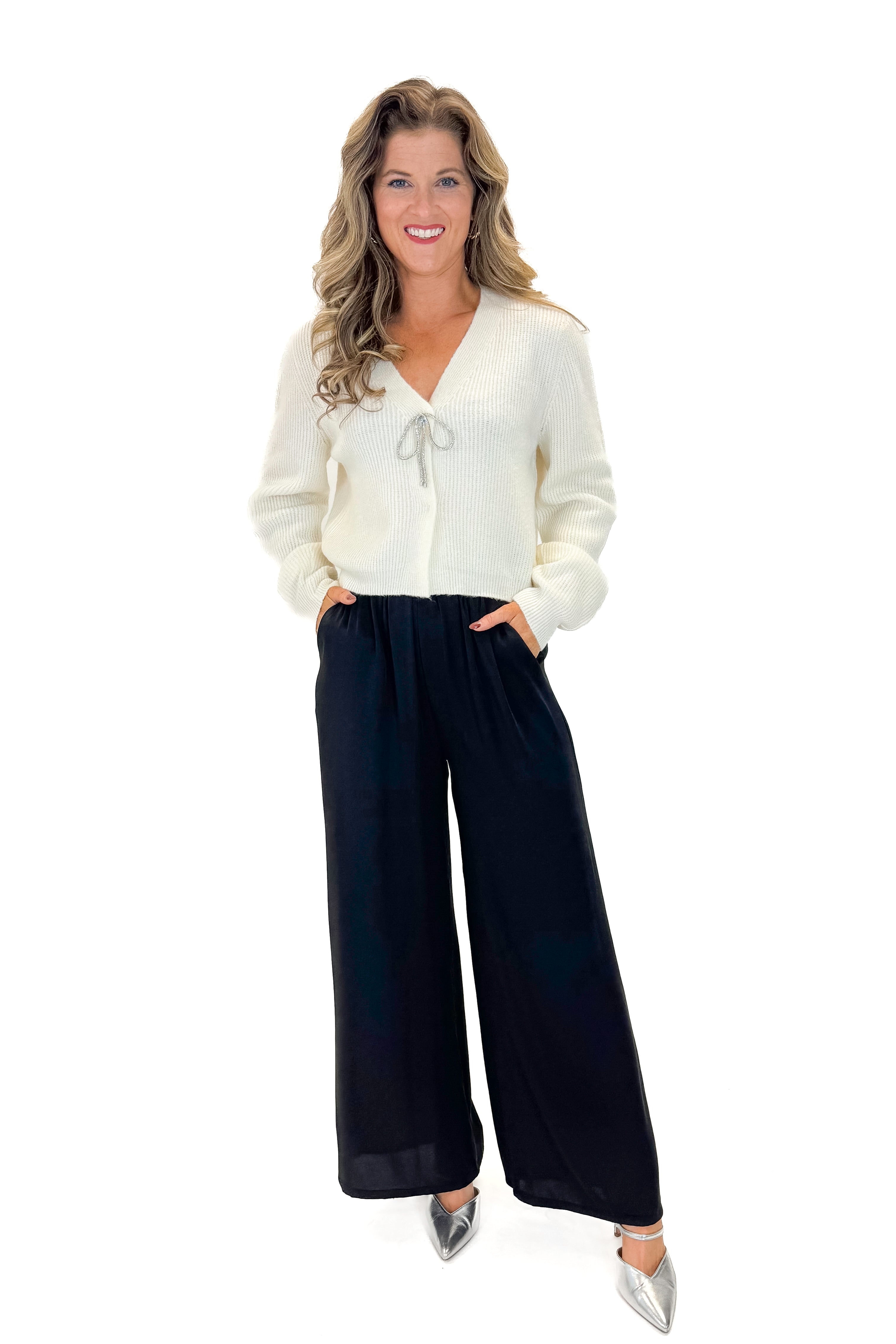 Front view of woman wearing sweater with Black Satin Pants against white studio background.