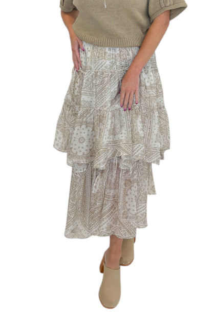 Front view of woman wearing Swagger Boutique’s Taupe Bandana Print Tiered Skirt with sweater against white studio background.