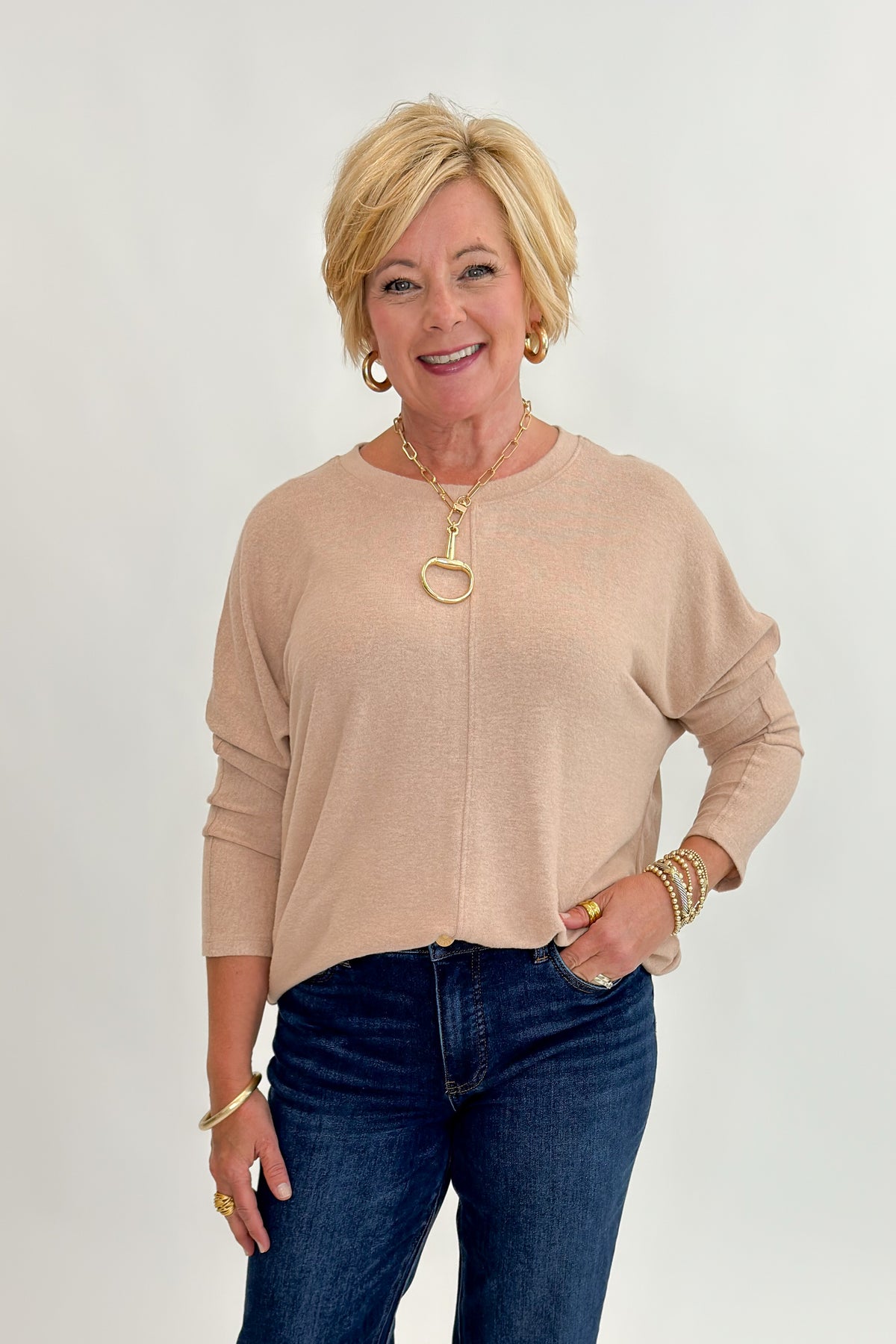 Front view of woman wearing Swagger Boutique’s Taupe Brushed Center Seam Top with jeans against white studio background.