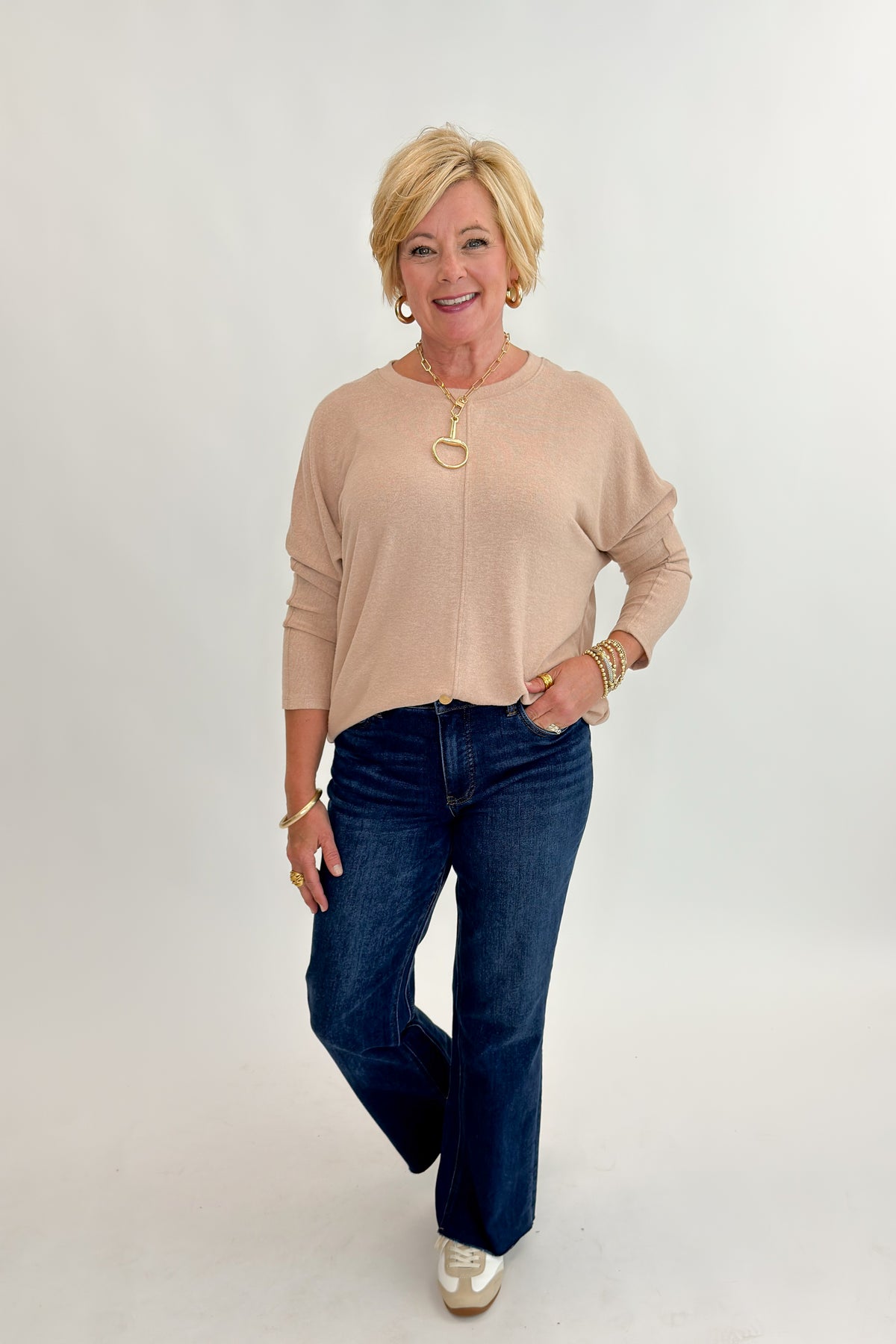 Front view of woman wearing Swagger Boutique’s Taupe Brushed Center Seam Top with jeans against white studio background.