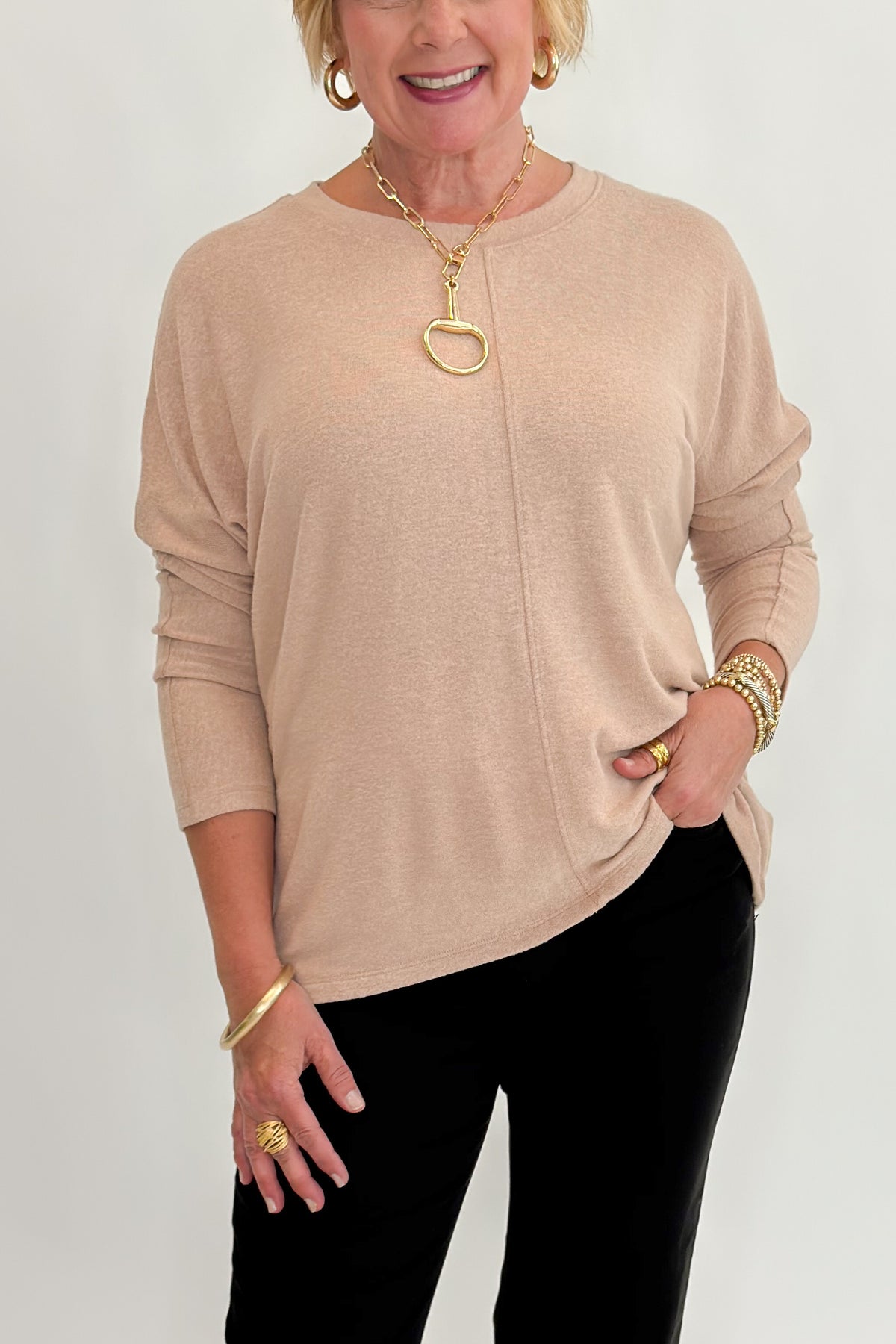 Front detail view of woman wearing Swagger Boutique’s Taupe Brushed Center Seam Top with jeans against white studio background.