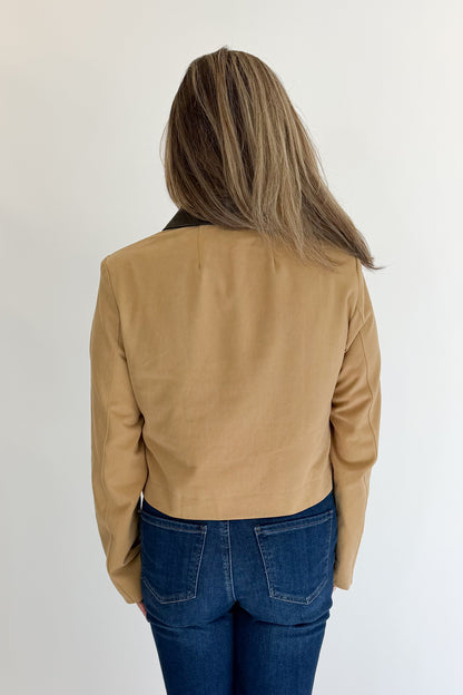 Back view of woman wearing Swagger Boutique’s Taupe Button Up Leather Collared Jacket with jeans against white studio background.