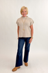Front view of woman wearing Swagger Boutique’s Taupe Mock Neck Short Sleeve Sweater with jeans against white studio background.