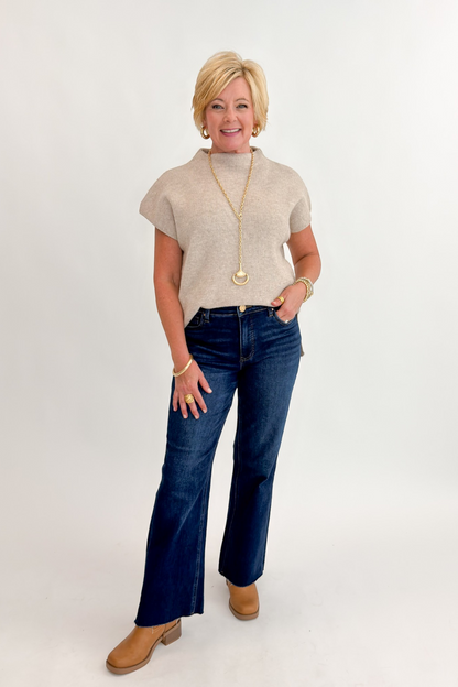 Front view of woman wearing Swagger Boutique’s Taupe Mock Neck Short Sleeve Sweater with jeans against white studio background.