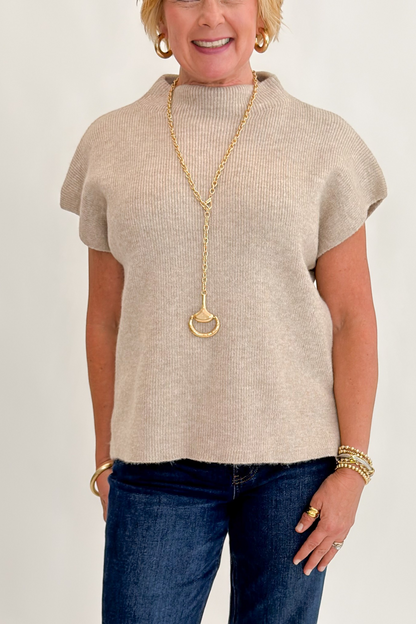Front detail view of woman wearing Swagger Boutique’s Taupe Mock Neck Short Sleeve Sweater with jeans against white studio background.