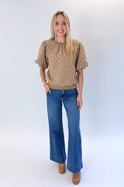 Front view of woman wearing Swagger Boutique’s Taupe Polka Dot Textured Top with jeans against white studio background.