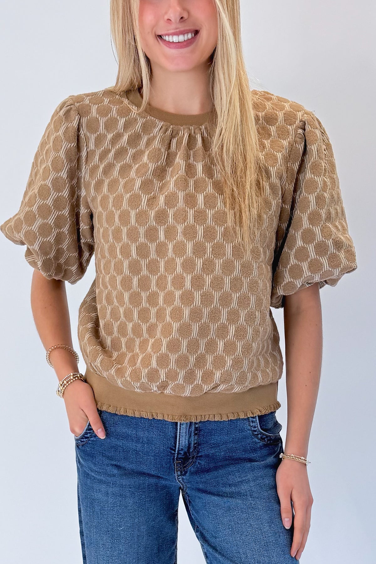 Front detail view of woman wearing Swagger Boutique’s Taupe Polka Dot Textured Top with jeans against white studio background.