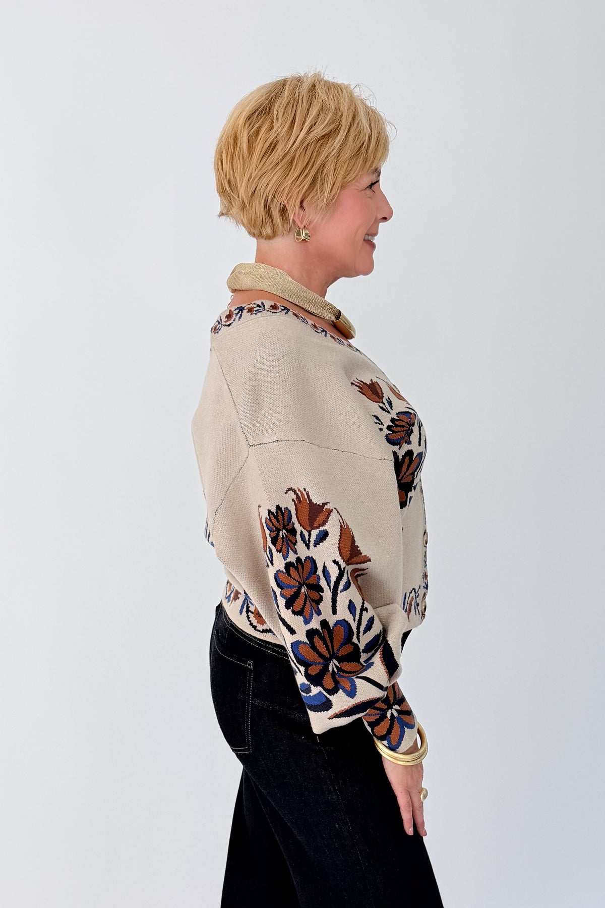 Side view of woman wearing Swagger Boutique’s Taupe Printed V-Neck Cardigan with jeans against white studio background.