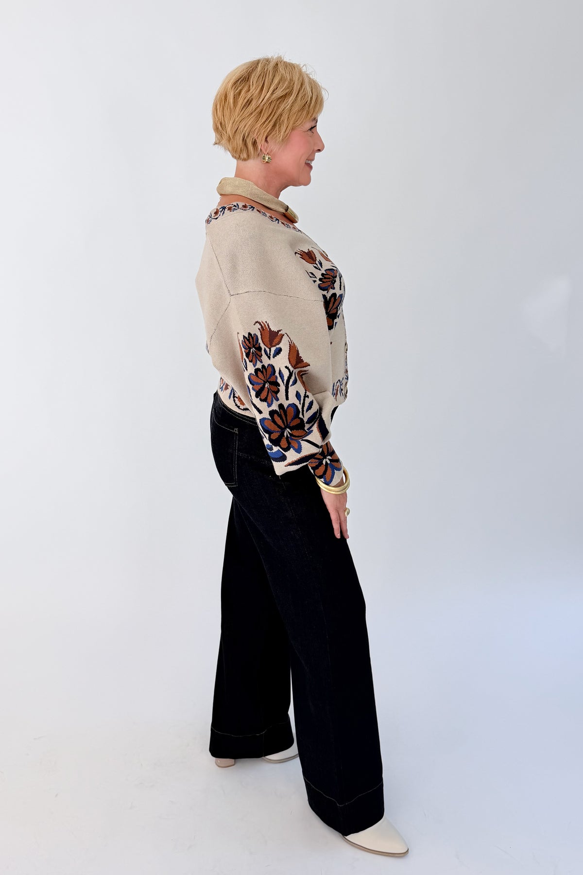 Side view of woman wearing Swagger Boutique’s Taupe Printed V-Neck Cardigan with jeans against white studio background.