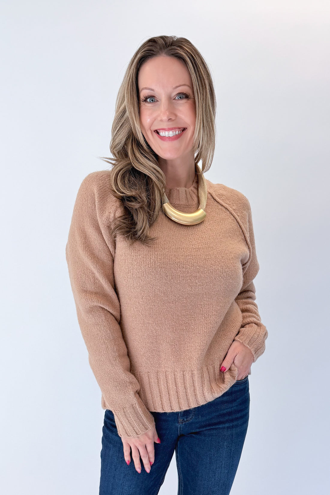 Front view of woman wearing Swagger Boutique’s Taupe Ribbed Hem Sweater with jeans against white studio background.