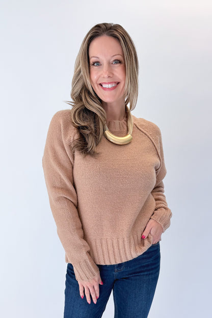 Front view of woman wearing Swagger Boutique’s Taupe Ribbed Hem Sweater with jeans against white studio background.