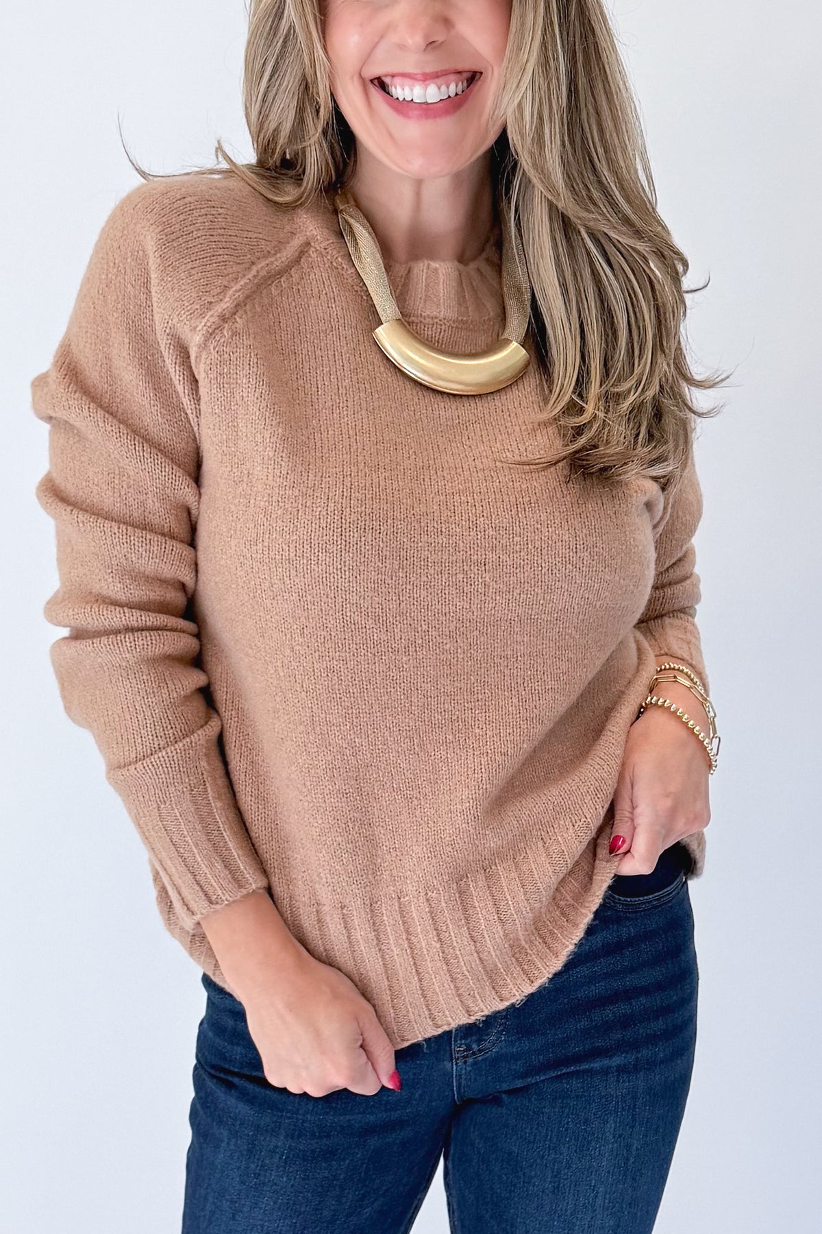 Front detail view of woman wearing Swagger Boutique’s Taupe Ribbed Hem Sweater with jeans against white studio background.