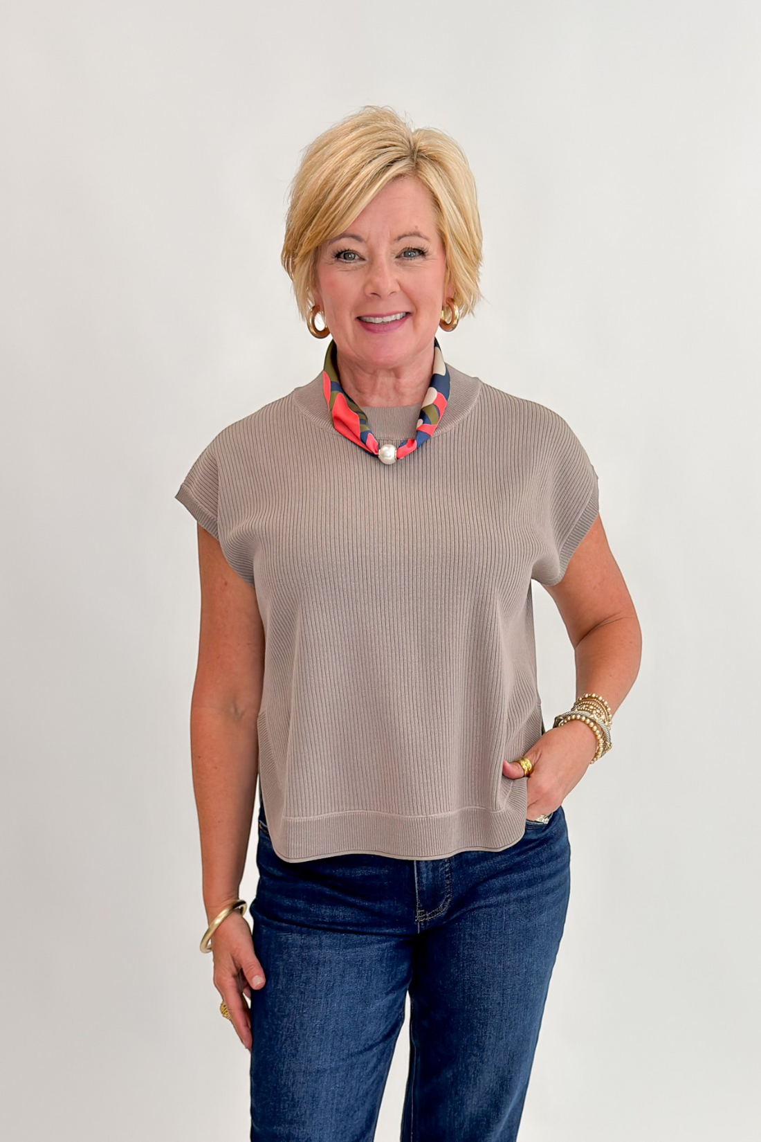 Front view of woman wearing Swagger Boutique’s Taupe Ribbed Short Sleeve Sweater by Entro with jeans against white studio background.