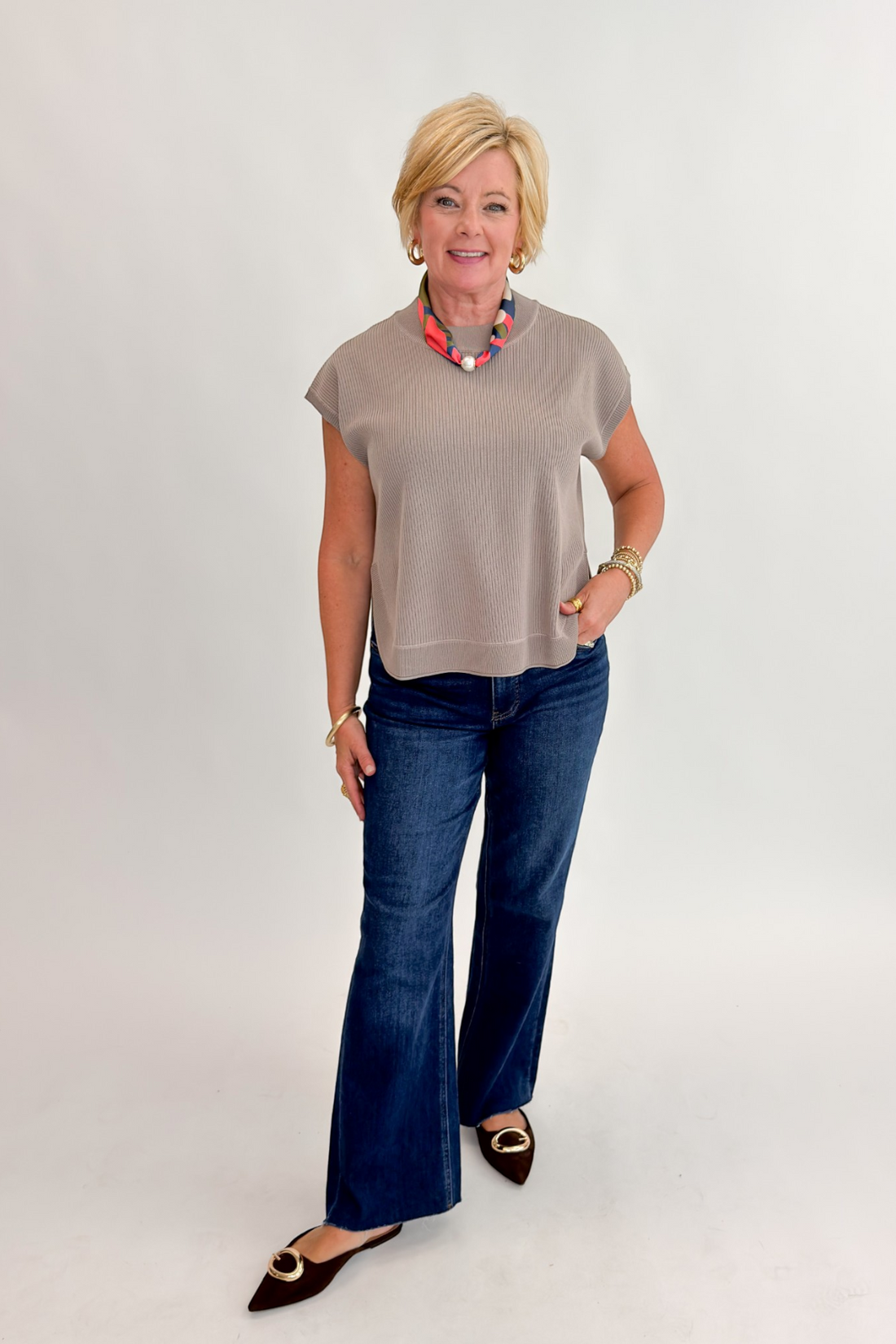 Front view of woman wearing Swagger Boutique’s Taupe Ribbed Short Sleeve Sweater by Entro with jeans against white studio background.