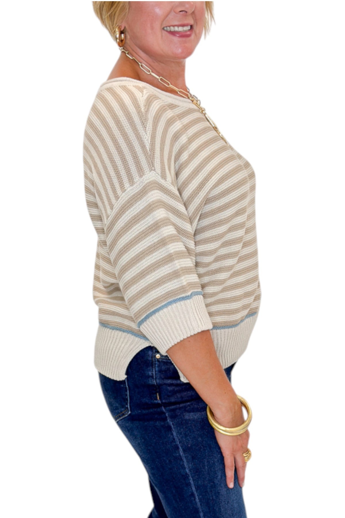 Side detail view of woman wearing Swagger Boutique’s Taupe Striped Short Sleeve Sweater with jeans against white studio background.