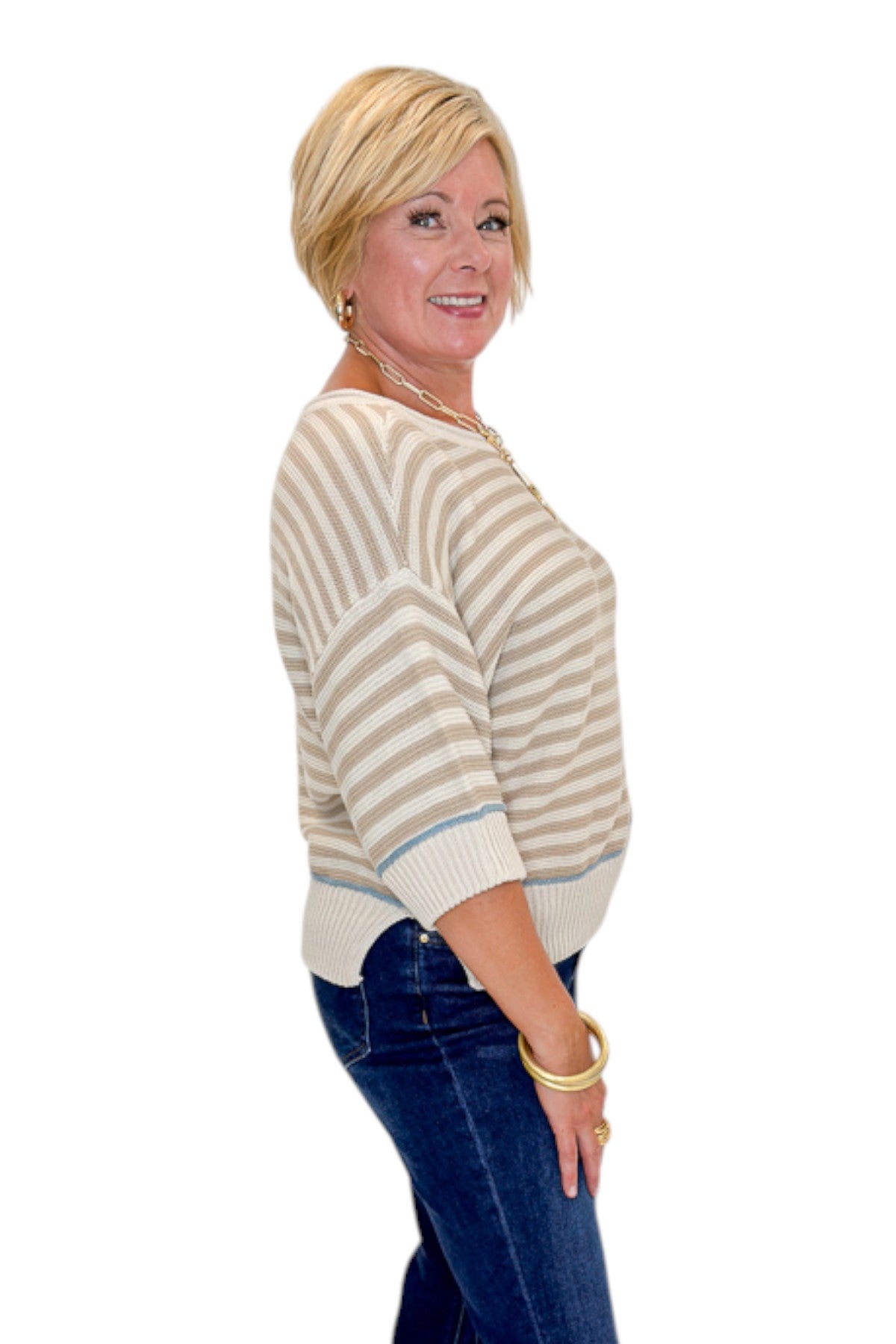 Side view of woman wearing Swagger Boutique’s Taupe Striped Short Sleeve Sweater with jeans against white studio background.