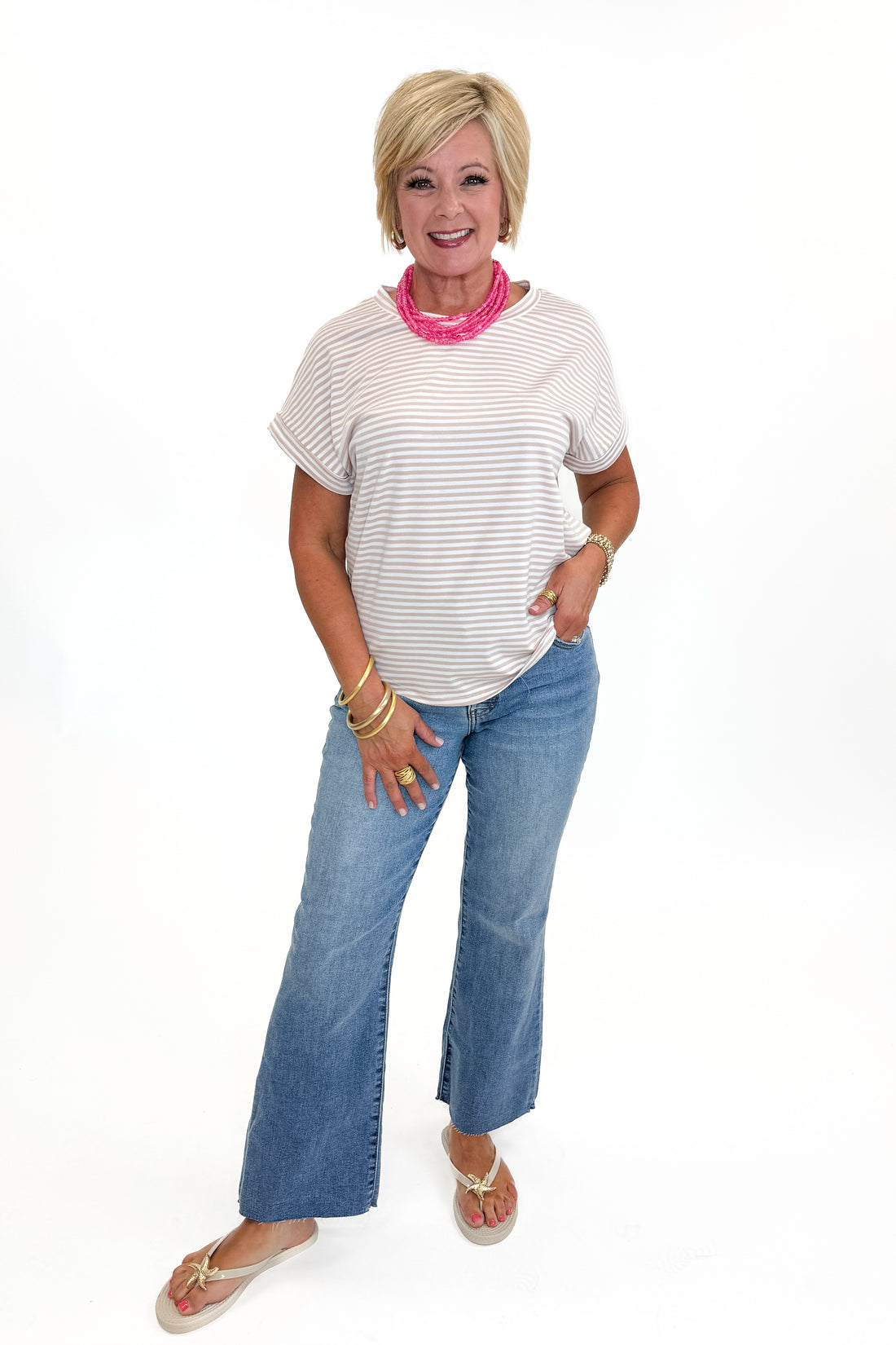 Front view of woman wearing Swagger Boutique’s Taupe &amp; White Striped Short Sleeve Top with jeans against white studio background.