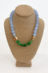 front view of beaded necklace featuring light blue round beads paired with translucent green beads on a beige display.