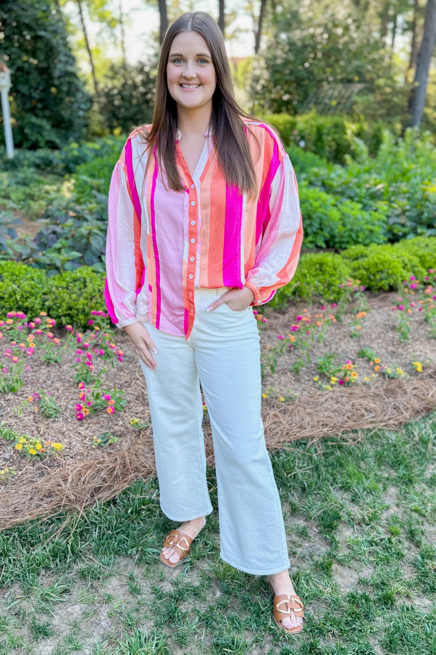 Front view of woman wearing Swagger Boutique’s Orange &amp; Pink Striped Top with jeans standing outside.