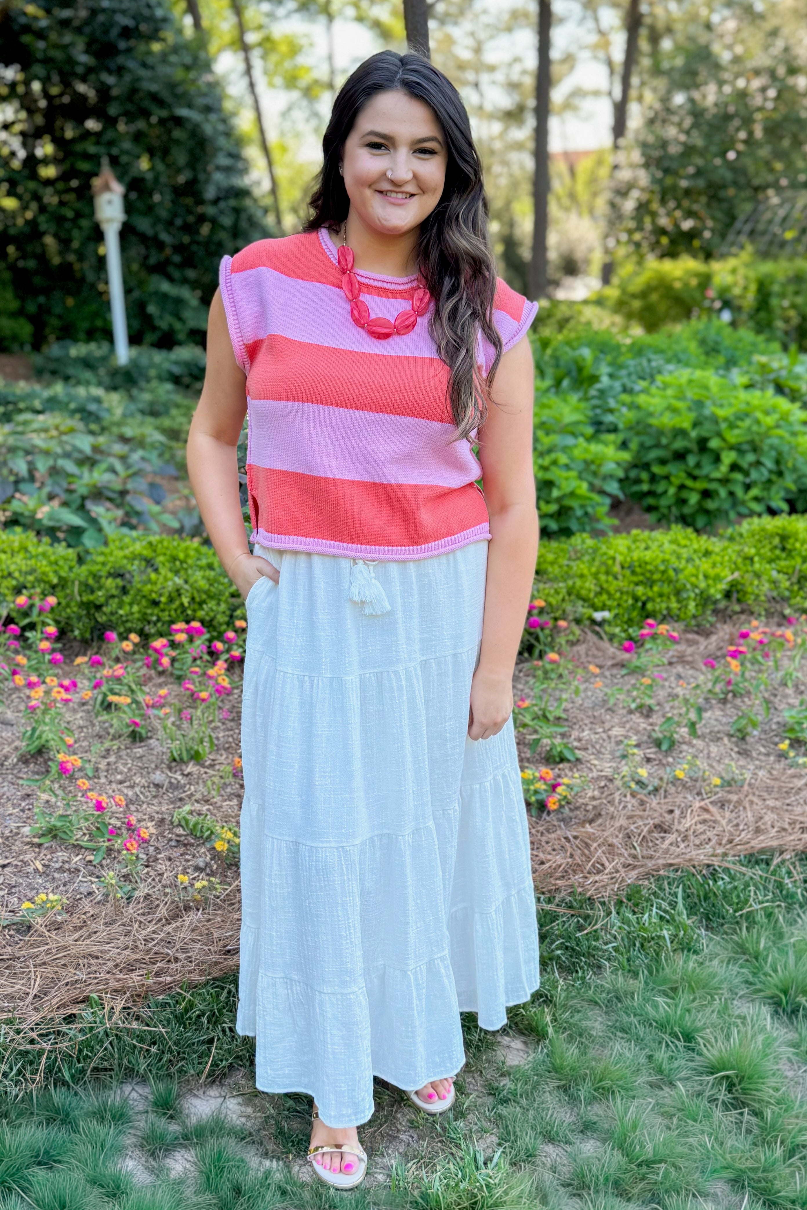 Front view of woman wearing Thank Me Later Pink &amp; Orange Striped Cap Sleeve Sweater by Entro with white skirt outside at a park.