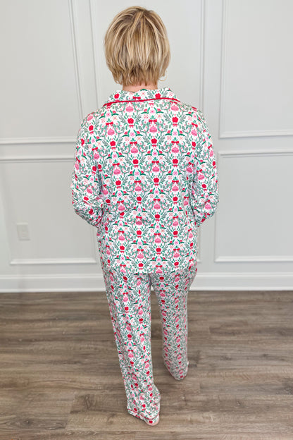 Back view of the Trimmed With Joy Charlotte Pajama Set, showcasing the allover Christmas floral print with red flowers, green foliage, and pink holiday details. The long-sleeve pajama top has a relaxed fit, paired with matching full-length pants.