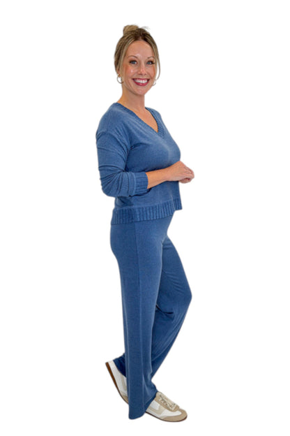 Side view of woman wearing Swagger Boutique’s True Navy Courtney Long Sleeve Top by Z Supply with True Navy Dawn Smocked Pants by Z Supply against white studio background.