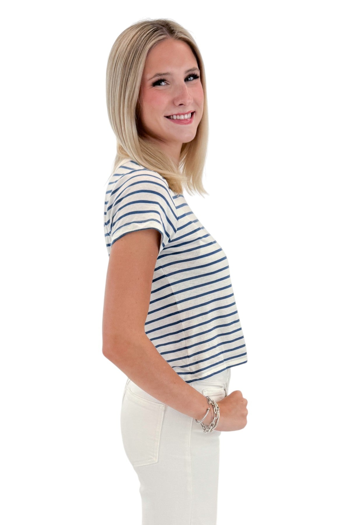 Side view of woman wearing Swagger Boutique’s True Navy Junie Striped Tee by Z Supply with jeans against white studio background.