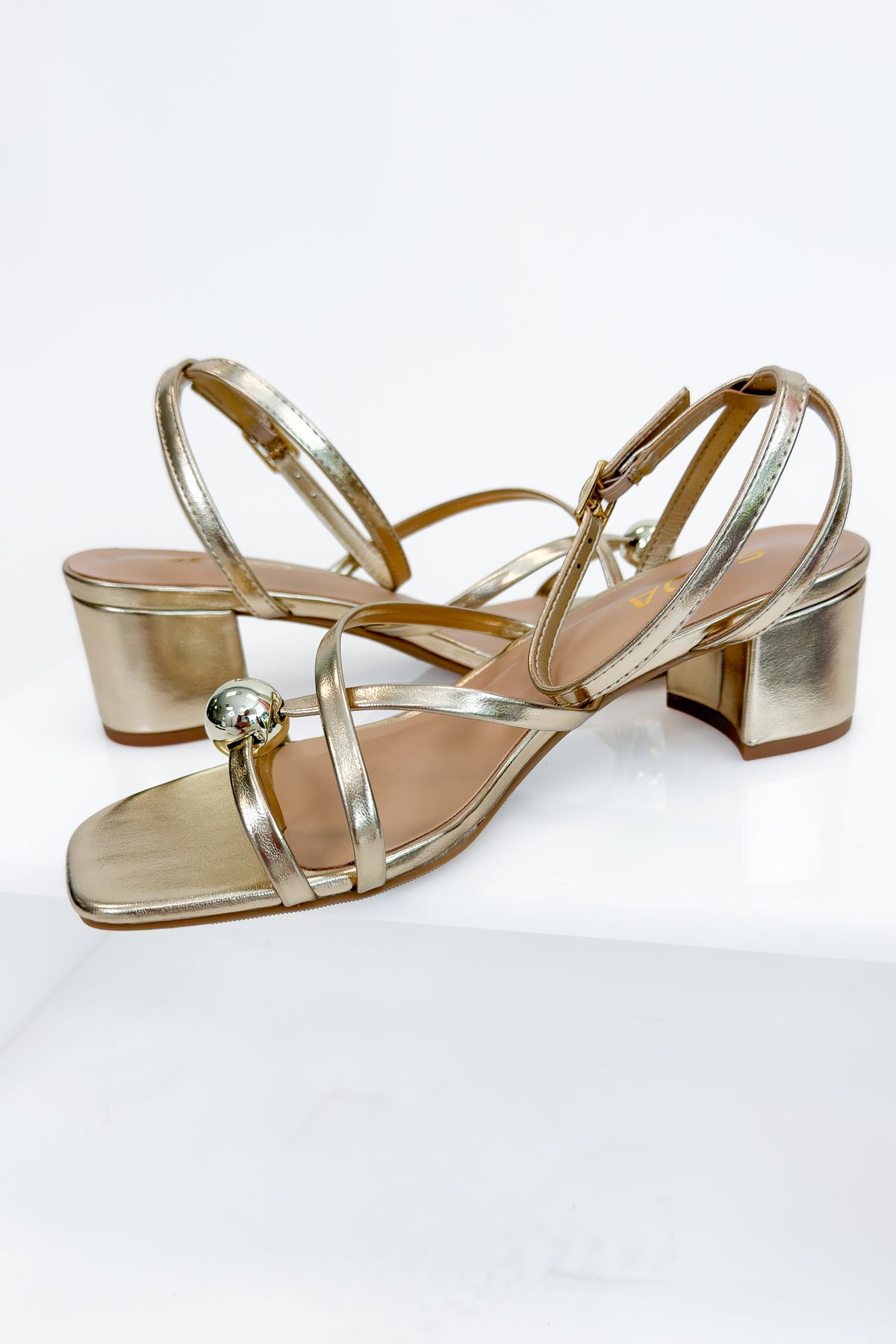 Tuari- Gold Ball Detail Cross Strap Heels against studio background side view.