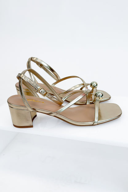 Tuari- Gold Ball Detail Cross Strap Heels against studio background side view.