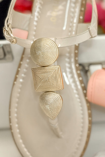 Twinkle- Bone With Gold Charms Sandal with travel accessories against white studio background front detail view.