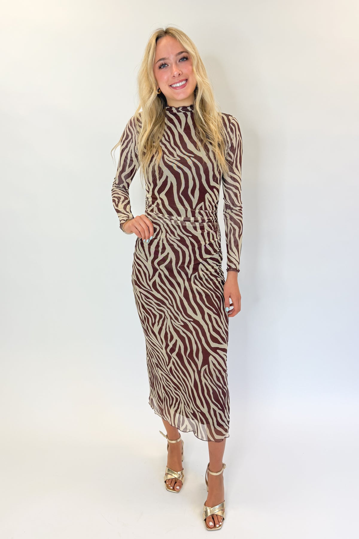 Front view of woman wearing Swagger Boutique’s Velvet Rouge Sevilla Zebra Mesh Midi Dress by Z Supply with heels against white studio background.