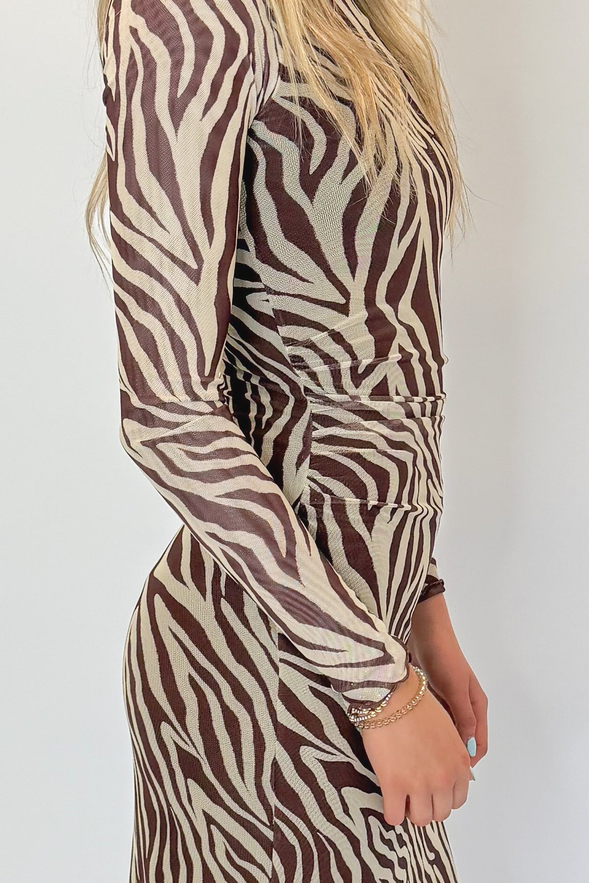 Side detail view of woman wearing Swagger Boutique’s Velvet Rouge Sevilla Zebra Mesh Midi Dress by Z Supply with heels against white studio background.