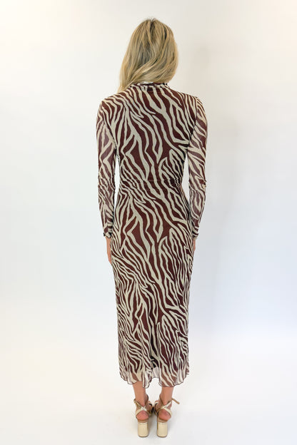 Back view of woman wearing Swagger Boutique’s Velvet Rouge Sevilla Zebra Mesh Midi Dress by Z Supply with heels against white studio background.