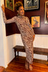 Front view of woman wearing Swagger Boutique’s Velvet Rouge Sevilla Zebra Mesh Midi Dress by Z Supply with heels at a restaurant waiting area.