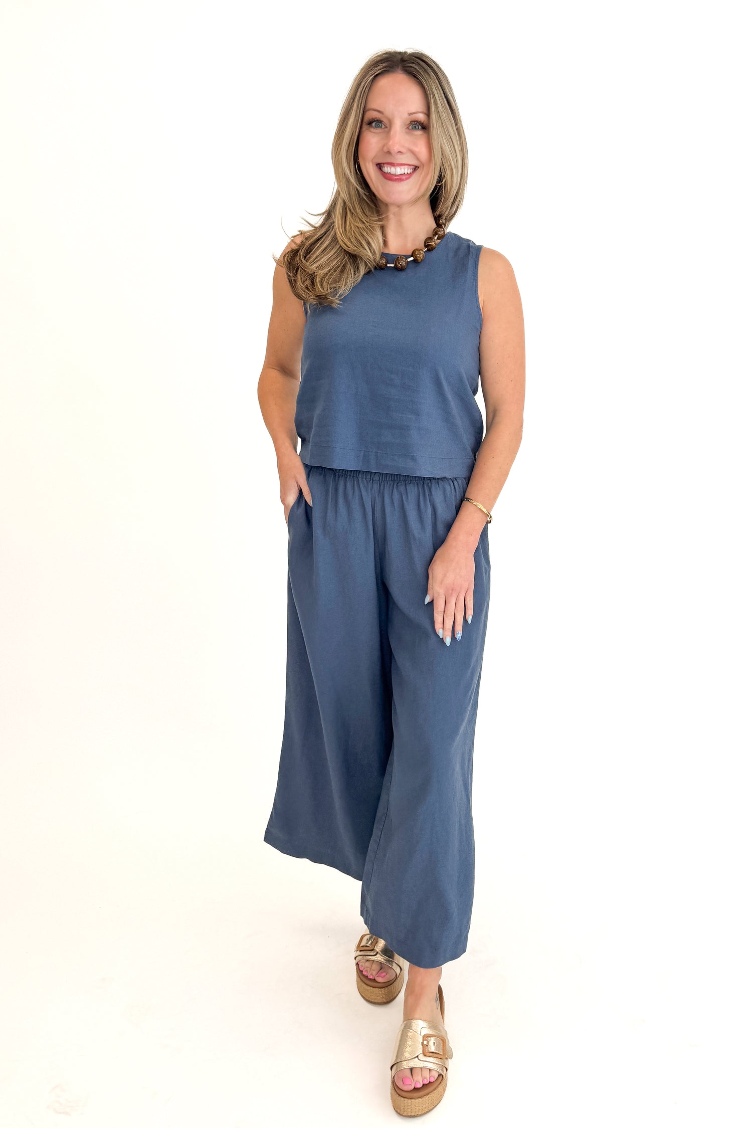 Front view of woman wearing Vintage Indigo Scout Linen Pants by Z Supply with matching Vintage Indigo Sloane Linen Top by Z Supply against white studio background.