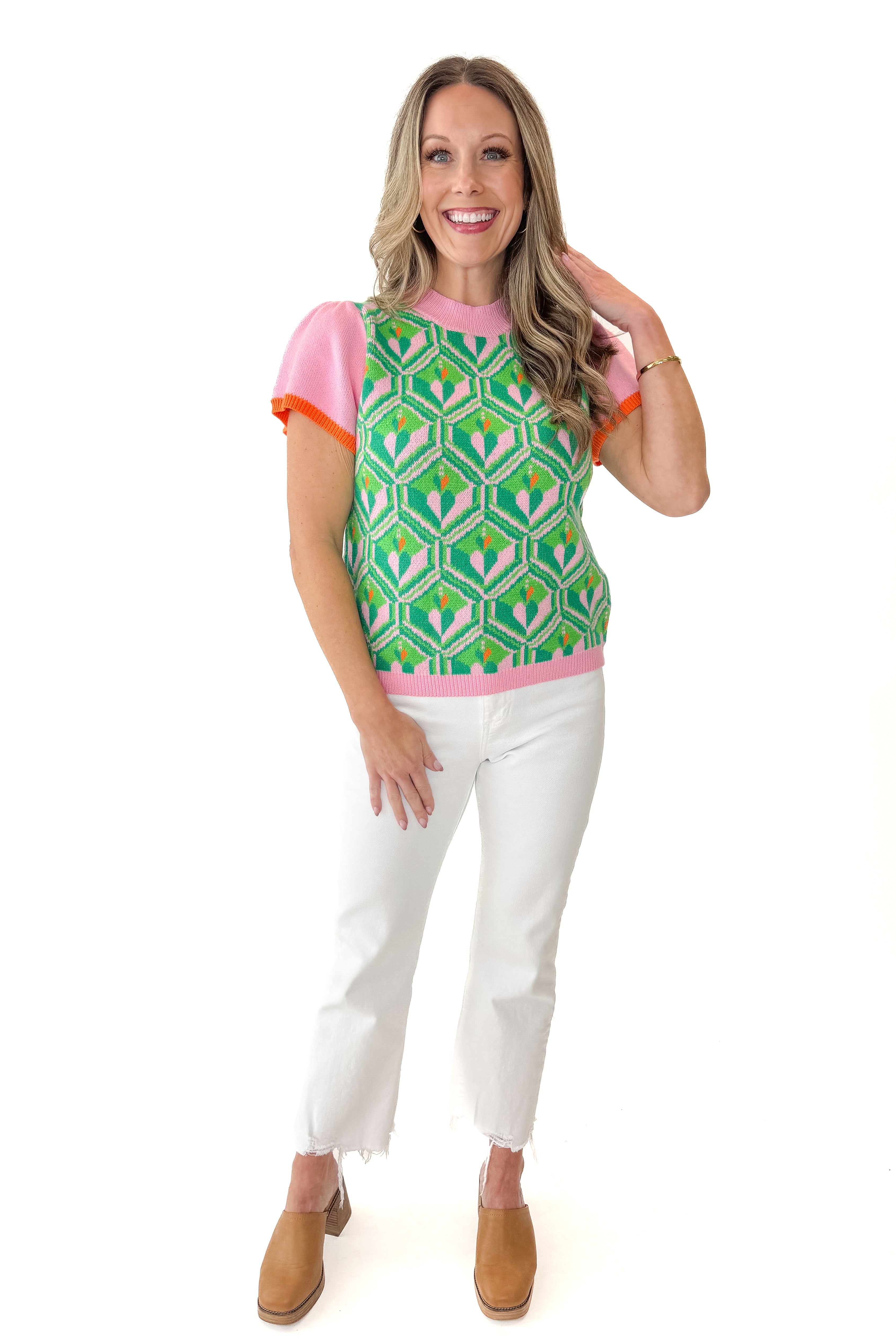 Front view of woman wearing Pink and Green Printed Short Sleeve Sweater with jeans against white studio background.