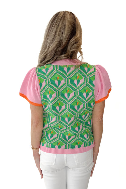 Back view of woman wearing Pink and Green Printed Short Sleeve Sweater with jeans against white studio background.