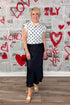 Front view of woman wearing Cream & Black Polka Dot Sleeveless Sweater with a black skirt against Valentine&
