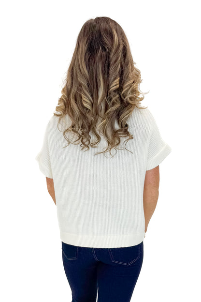 Back view of woman wearing Off White 1/2 Zip Short Sleeve Sweater with jeans against white studio background.