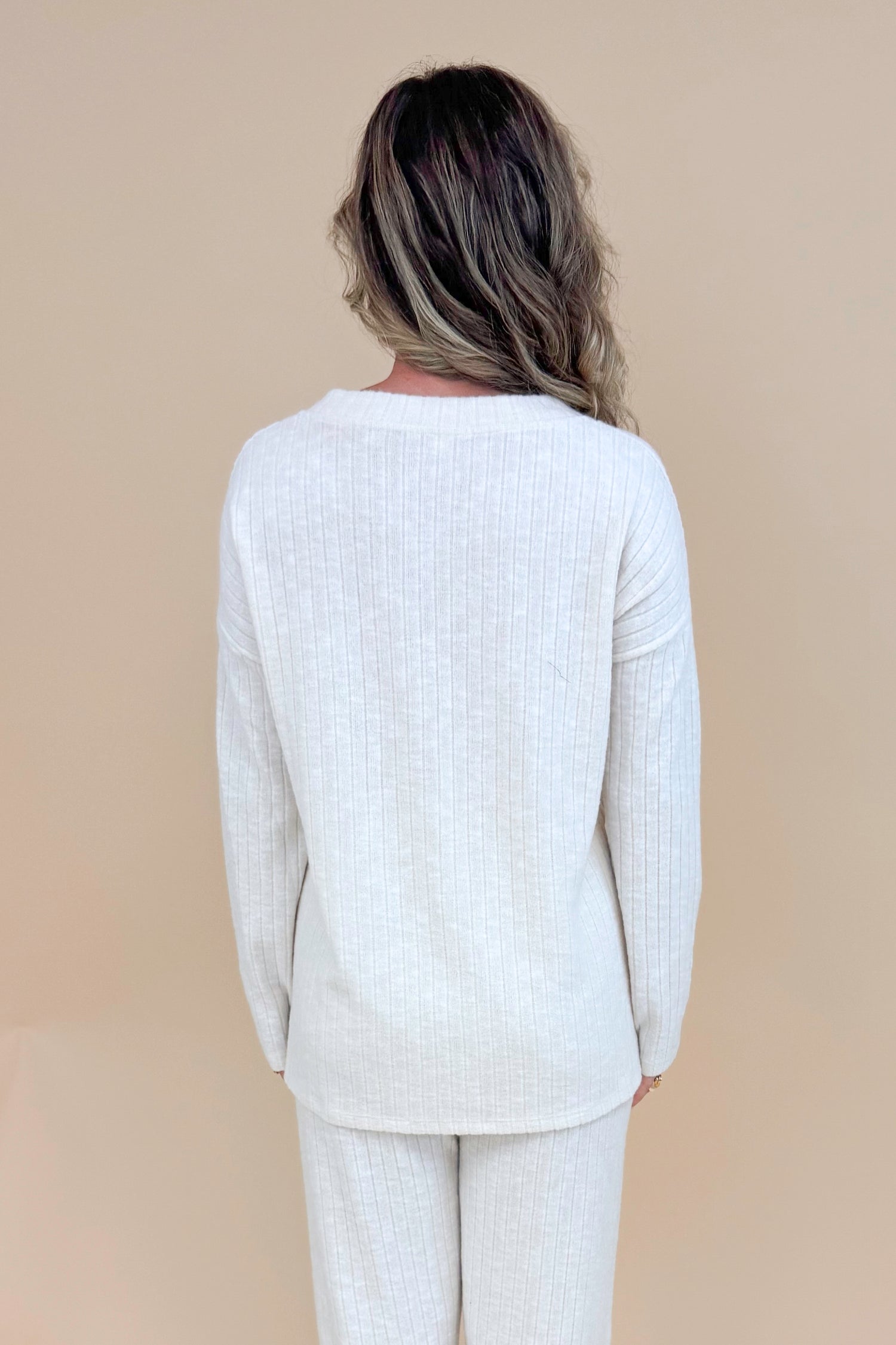Back view of model wearing cream ribbed lounge long sleeve top.
